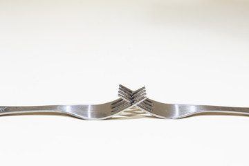 Stainless steel forks crossed on white background with copy space – Shiny silver kitchen tools...