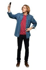 Full-length shot of Blonde man making a selfie over isolated white background