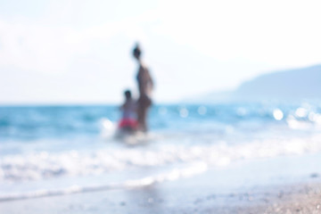 Mother and daughter spend time on a beach near the sea. Blurred people background. Space for your text. Summer time. Family vacation. 