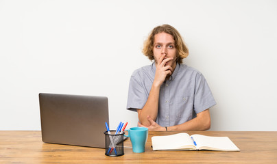Blonde man with a laptop surprised and shocked while looking right