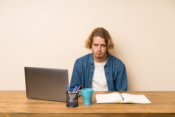 Blonde man with a laptop sad