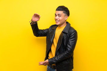 Young man over isolated yellow background holding copyspace to insert an ad