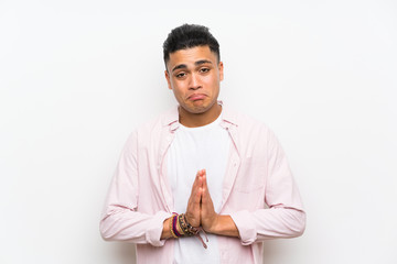 Young man over isolated white wall pleading