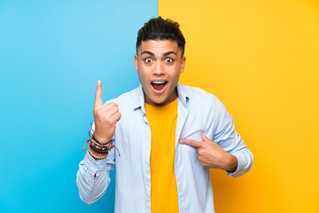 Young man over isolated colorful background with surprise facial expression