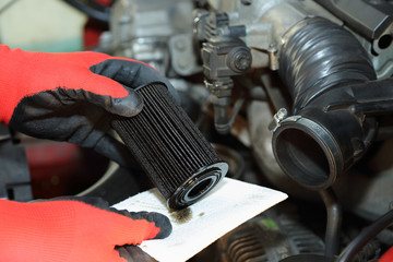 Mechanik wyjmuje filtr oleju w samochodzie osobowym.