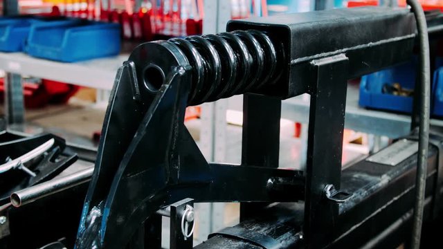 Worker managing spring coiling machine at factory. Industrial equipment