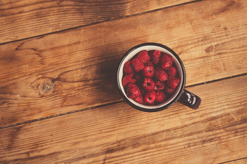 Fresh raspberries background closeup photo. Red raspberries in metal cup on wooden table. Vintage style