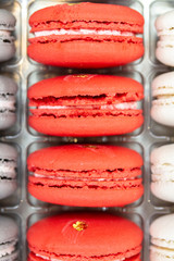 Sweet almond pastry biscuits dessert. French macaroons vertical row red crimson crimson. Two-colored macaroon with cream in the middle. Appetizing beautiful smooth sweets
