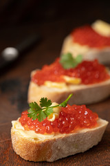 canapés with russian red caviar on wooden table. close up