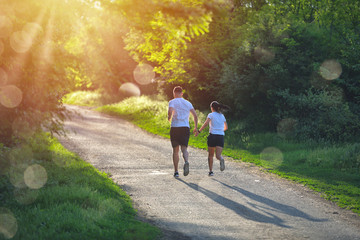 Young people jogging and exercising in nature, in morning sunrise warm light