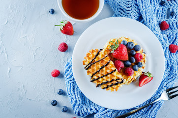 Waffeles with berries and mint leaf and a cup of tea