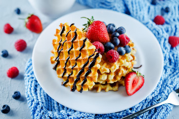 Waffeles with berries and mint leaf and a cup of tea