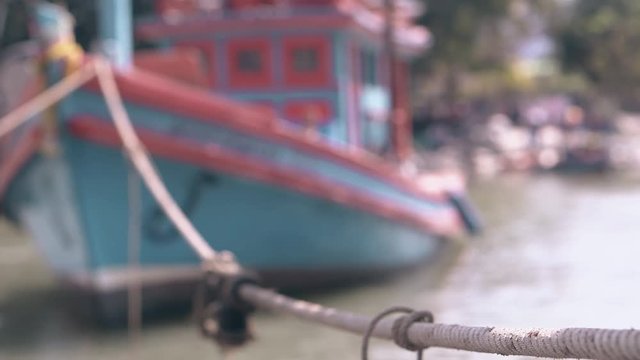 vintage ship rope connects traditional Asian fishing boat with moor in tranquil bay close view