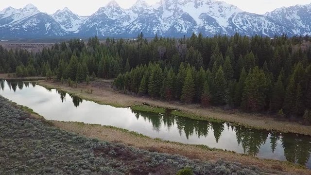Aerial, drone shot, over a river, towards the mountains, on a sunny, autumn evening, in Grand Teton national park, in Wyoming, USA