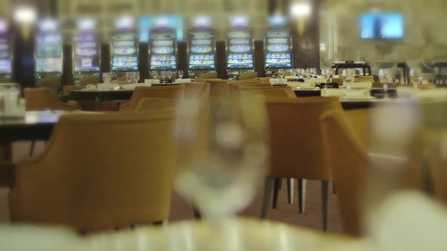 Empty tables with wine glasses in restaurant near slot machines in casino