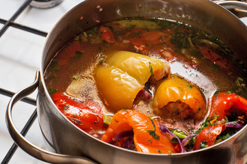 cooking  vegetarian stuffed sweet pepper with tomato in saucepan at cooker