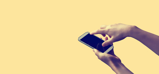 Person holding a white smartphone on a solid colored background © Tierney