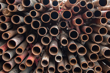 pile of round old red, brown, rusty metal pipes. rough surface texture