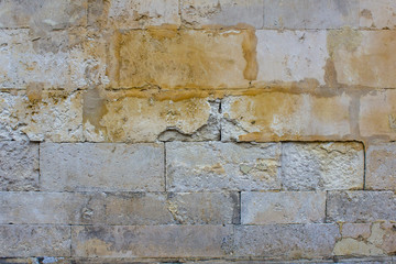 old damaged gray wall of large stone bricks with yellow spots of paint. rough surface texture