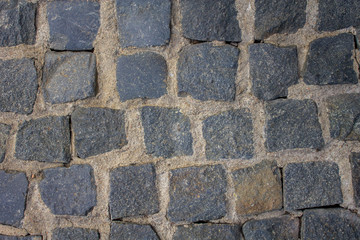 old stone pavement of blue stones of various shapes and sizes with light cement. rough surface texture