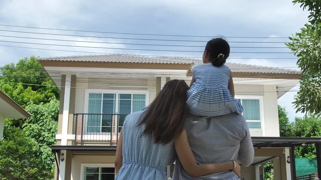 Happy Asian family. Father, mother and daughter near new home. Real estate background.