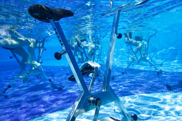 Fitness class. Water aerobics classes on exercise bikes in the pool