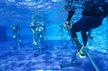 Touristen doing aqua aerobics on exercise bikes in swimming pool tropical hotel