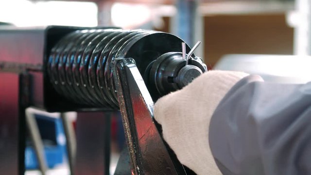 Worker hammering cotter pin into metal part during manual assemble