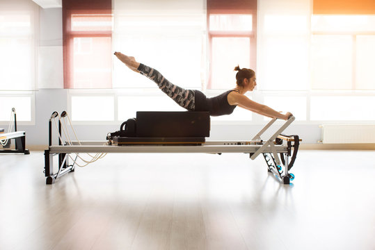 Pilates reformer workout exercises woman at gym indoor