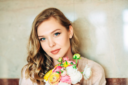 Portrait of beautiful young woman holding colorful buttercup flowers