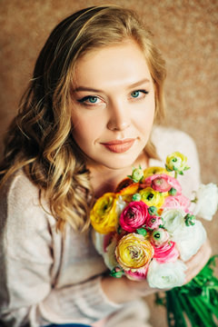 Portrait of beautiful young woman holding colorful buttercup flowers