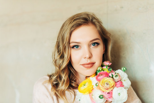 Portrait of beautiful young woman holding colorful buttercup flowers
