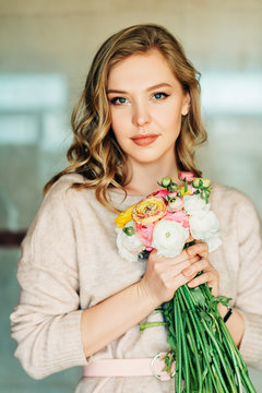 Portrait of beautiful young woman holding colorful buttercup flowers