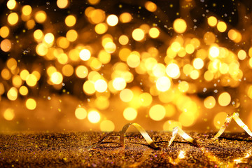 Golden glitter and streamer against black background. Space for text
