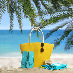 Different stylish beach accessories on sand near ocean