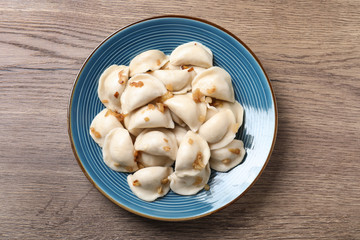 Plate of tasty cooked dumplings on wooden table, top view