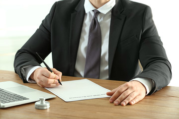 Male notary working with documents at wooden table, closeup