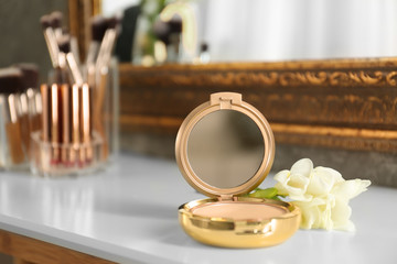 Luxury compact powder and flowers on dressing table, space for text. Interior element