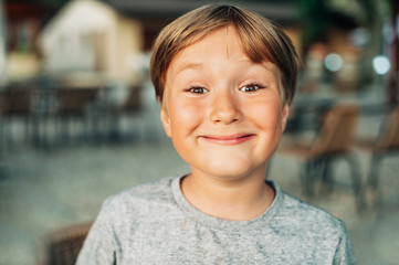 Outdoor close up portrait of 6-7 year old boy with funny facial expression
