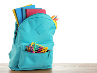 Bright backpack with school stationery on white background