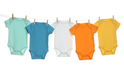 Colorful baby onesies hanging on clothes line against white background. Laundry day