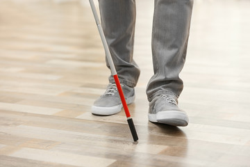 Blind person with long cane walking indoors, closeup. Space for text