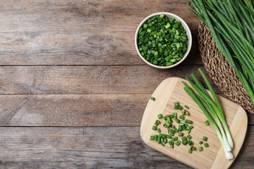 Flat lay composition with fresh green onions on wooden background. Space for text