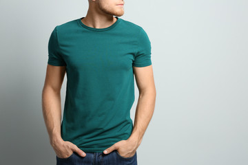 Young man wearing blank t-shirt on light background, closeup. Mockup for design