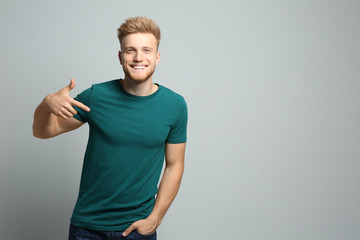 Young man wearing blank t-shirt on light background. Mockup for design