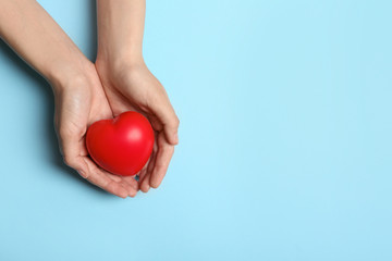 Woman holding heart on blue background, top view with space for text. Donation concept