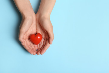 Woman holding heart on blue background, top view with space for text. Donation concept
