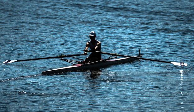 Single Rower In Racing Boat During Oar Stroke On Lake