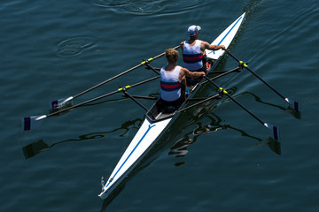 Two Male Rowers In A Double Racing Boat With Synchronous Oar Stroke - obrazy, fototapety, plakaty
