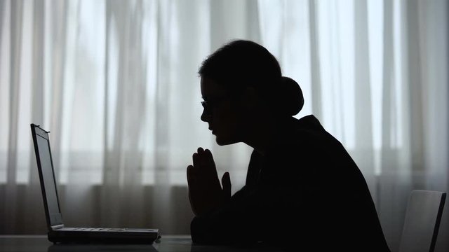 Nervous woman silhouette looking at laptop screen, sending data via internet